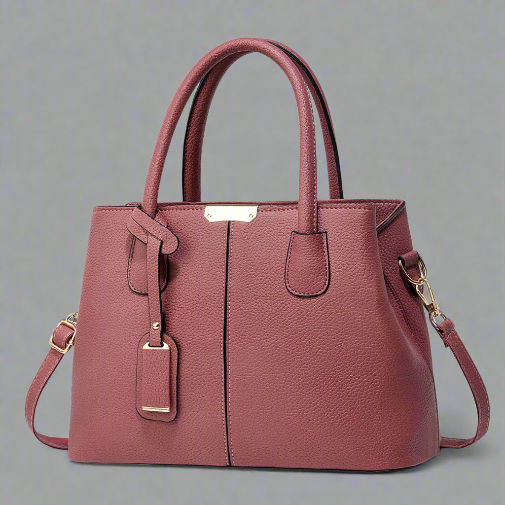Pink handbag with gold accents on a white background